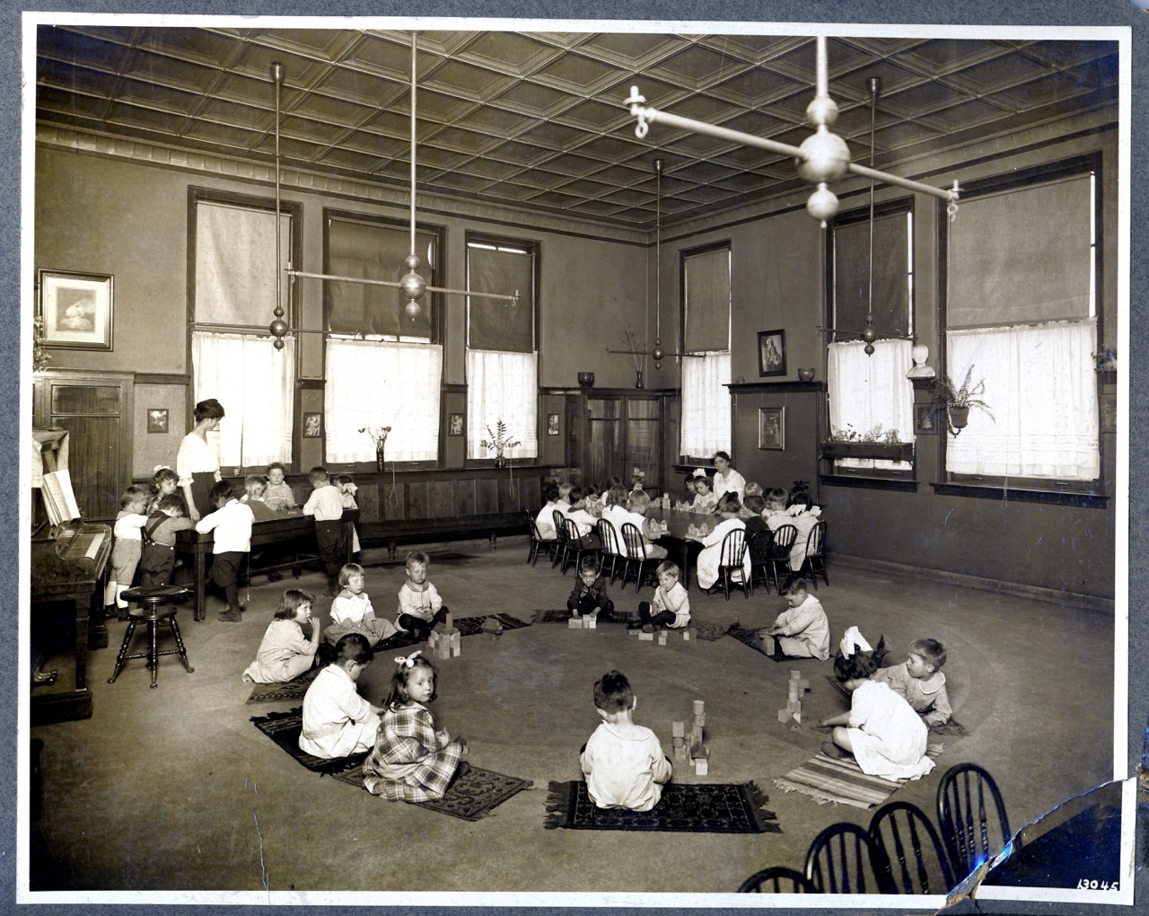 Student of the Chicago Kindergarten College teaching a Kindergarten class, circa 1900. Students are sitting in a circle and using Froebel Gifts.